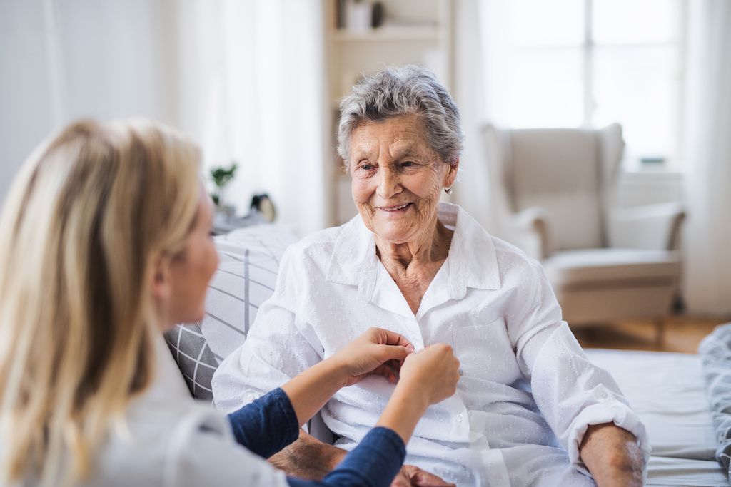 caregiver_helping_older_woman_button_blouse