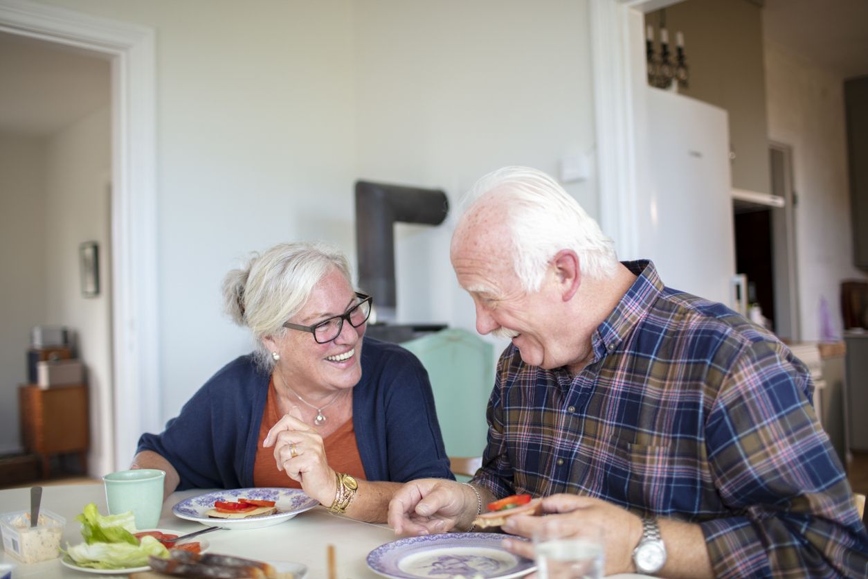 older couple laughing while eating
