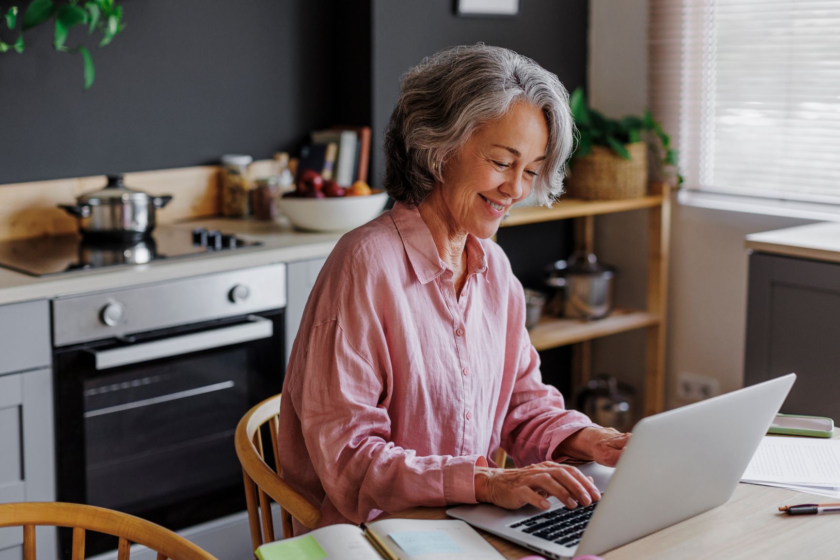 older woman smiling while typing on computer