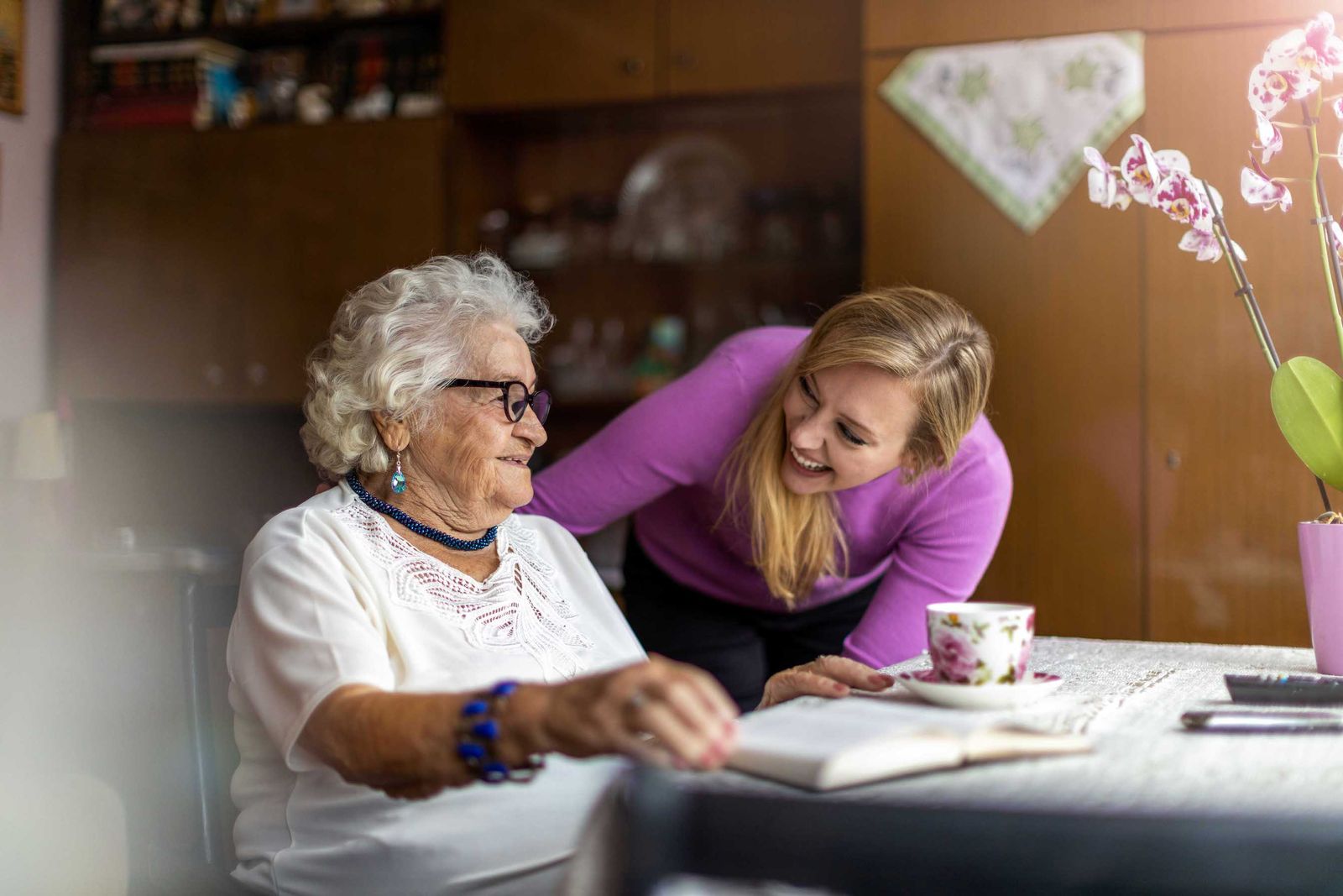 older woman reading at table with younger woman