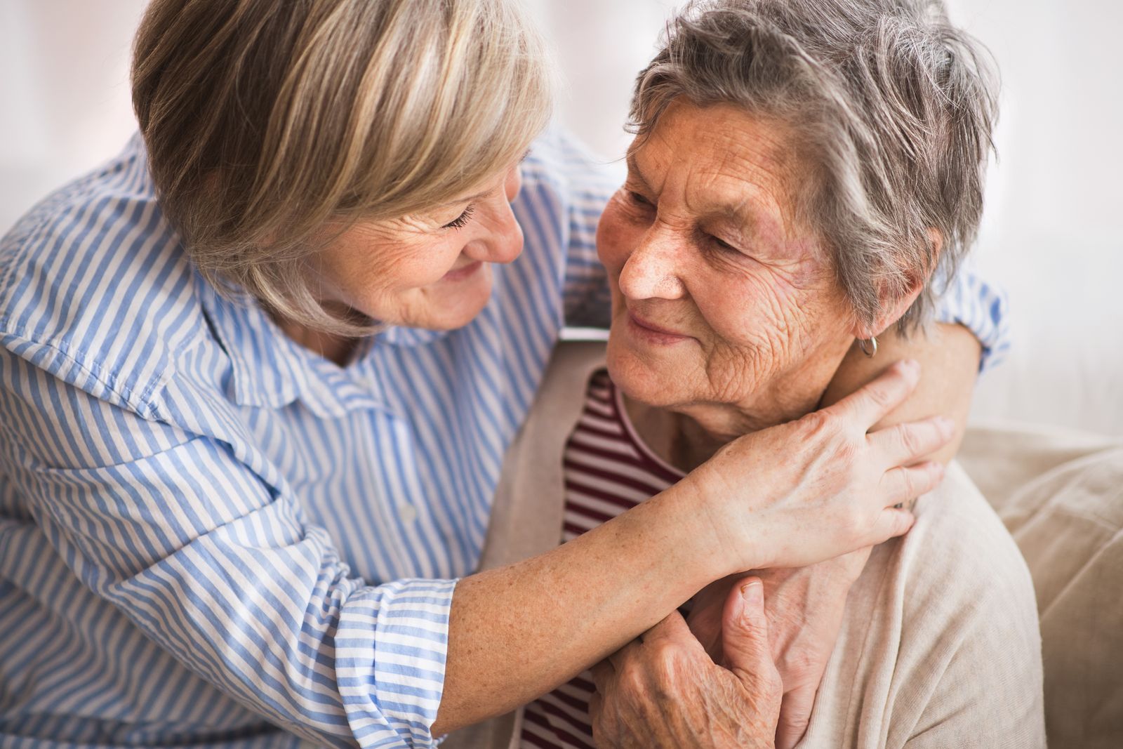 caregiver-embracing-older-adult-and-both-are-smiling