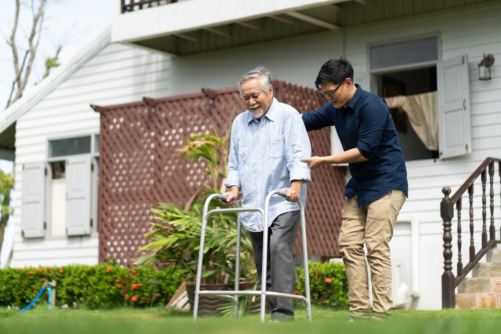adult son helping his father use a walker outside
