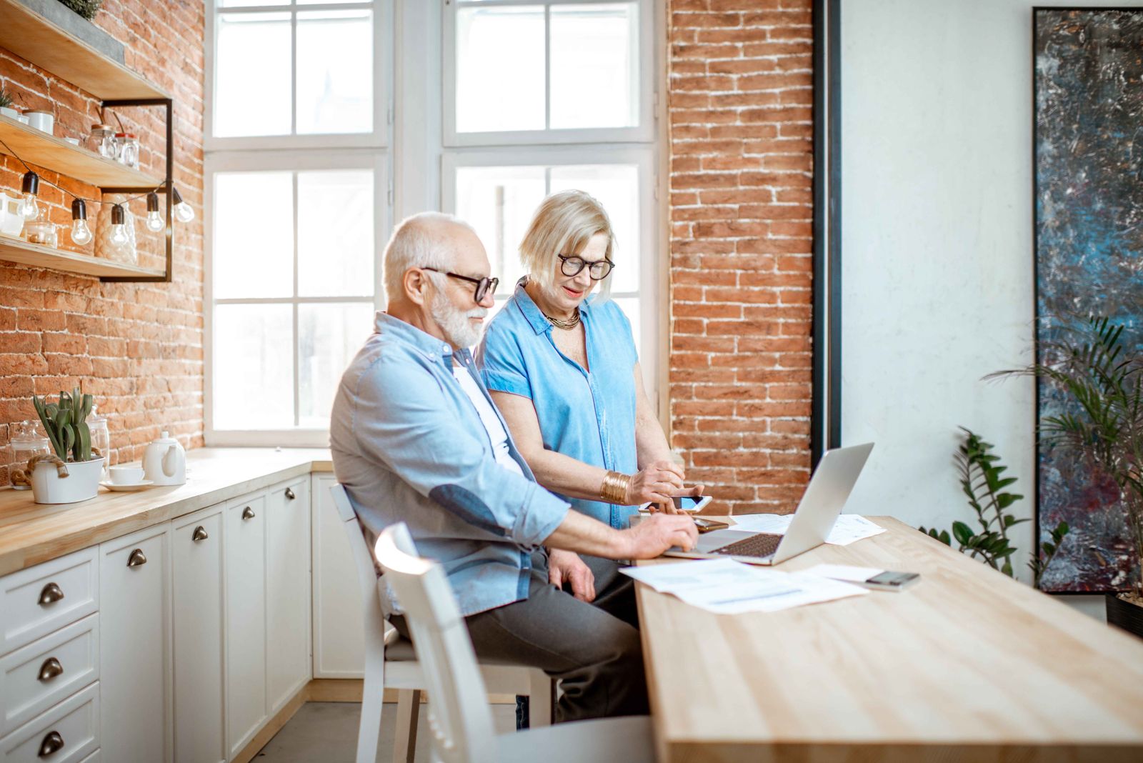 older couple sitting at a kitchen bar with a laptop
