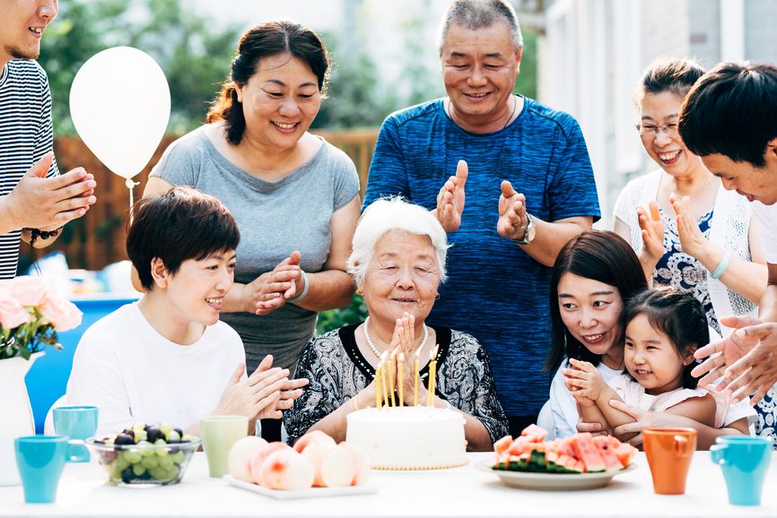 Older woman birthday cake outside with family