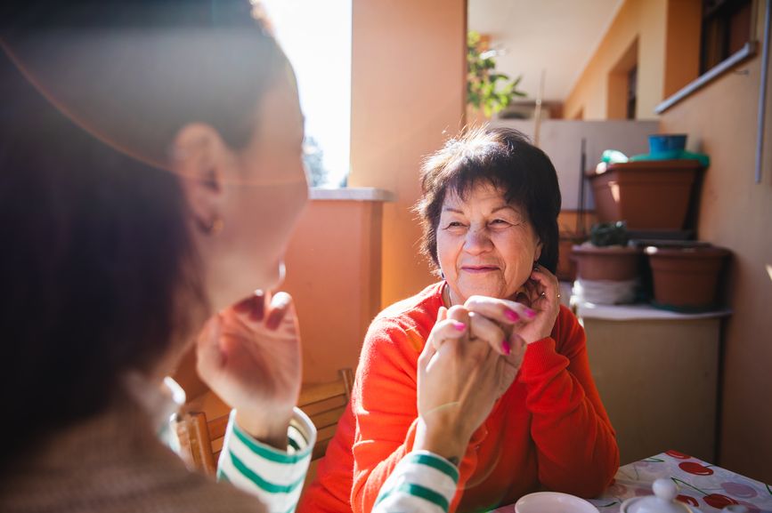 Older Woman and Young Woman Sitting at a Table Holding Hands