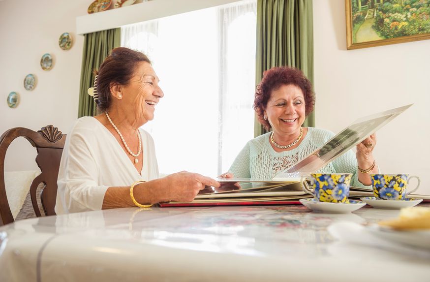 Two Older Women Looking at Pictures at Table